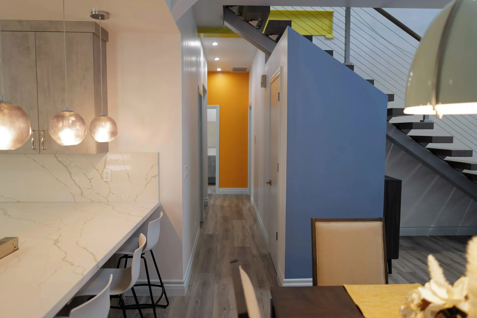 LOT14 HOUSE. Colored stair and hallway beneath a double-height ceiling beside the kitchen.