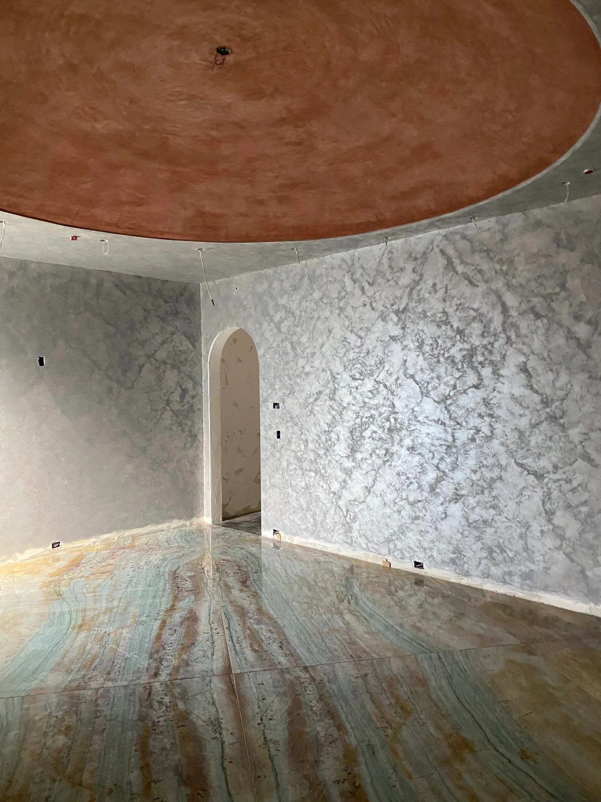 TUSCAN HOUSE. Silver walled dining room with a curved ceiling, arched opening, and stone floor.